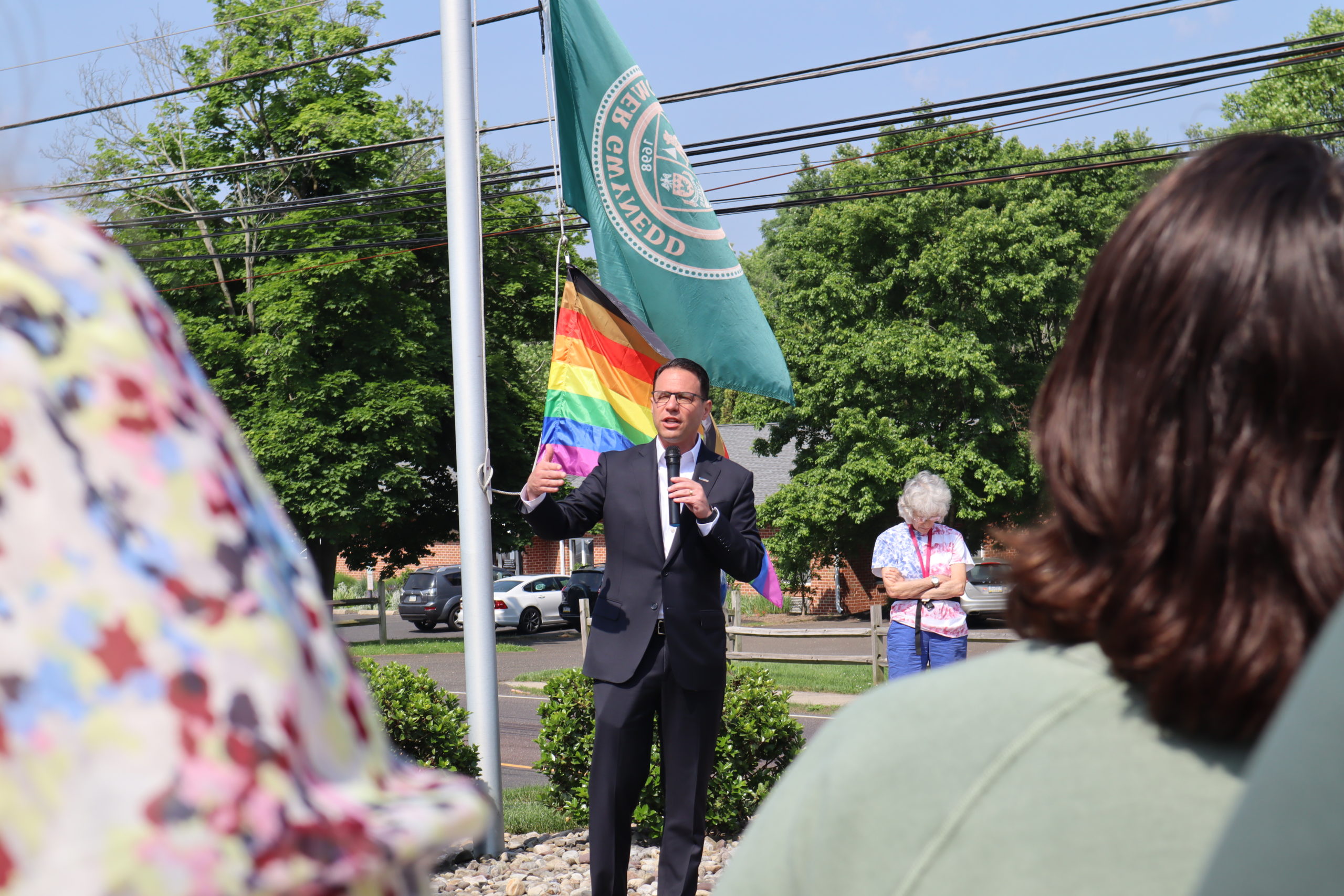 Josh speaking in front of a Pride flag