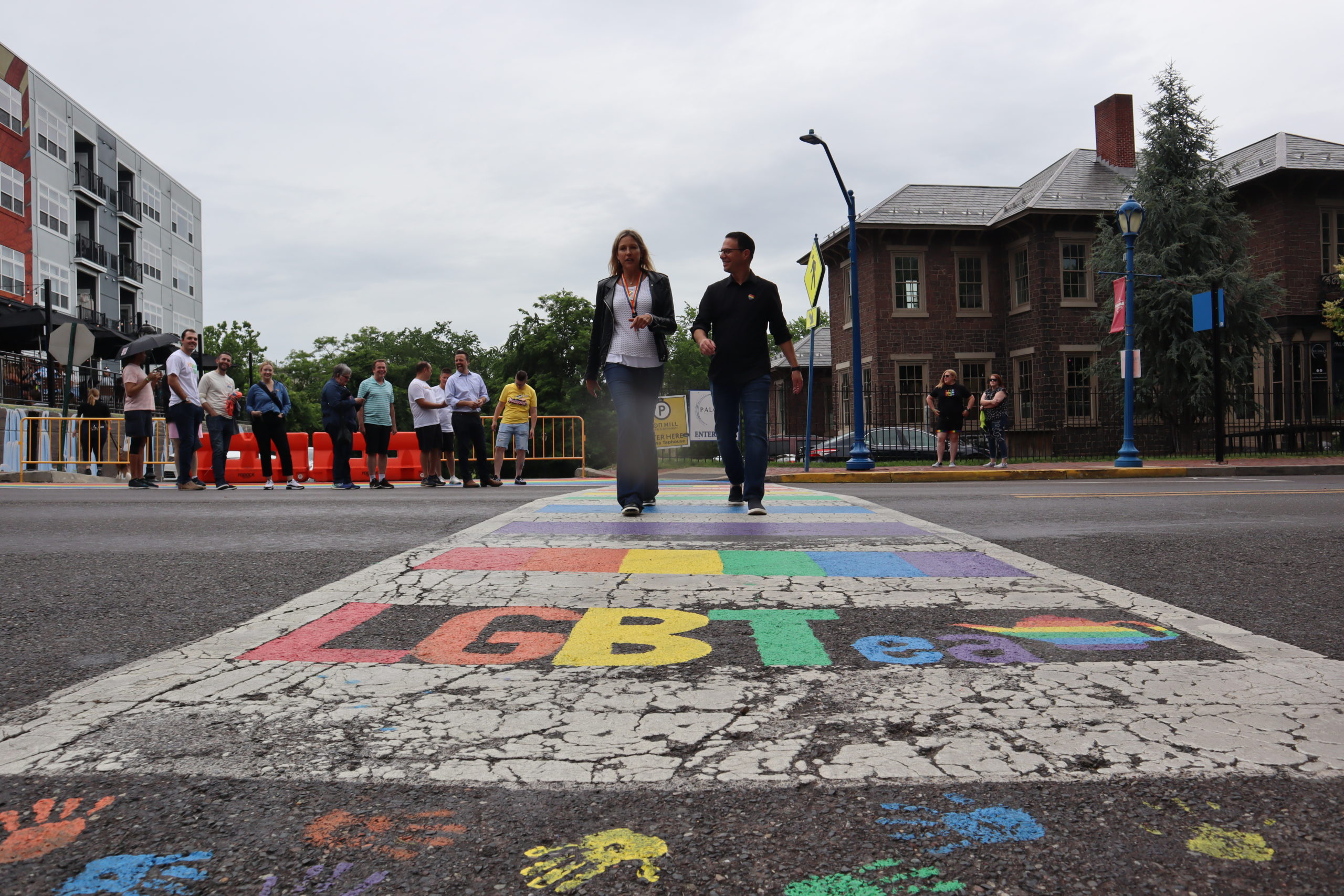 Josh walking with a woman across a rainbow crosswalk