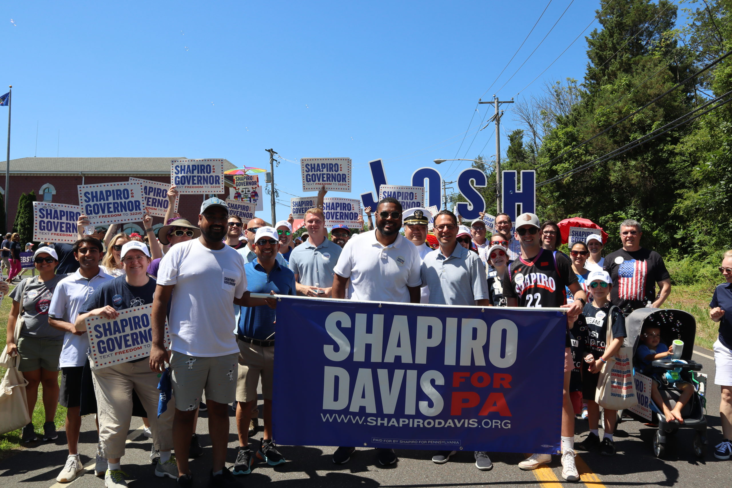 Josh and Austin holding a Shapiro Davis banner with parade marchers